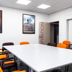 Salle de réunion moderne avec chaises orange et marron, décorée de posters inspirants sur les murs.